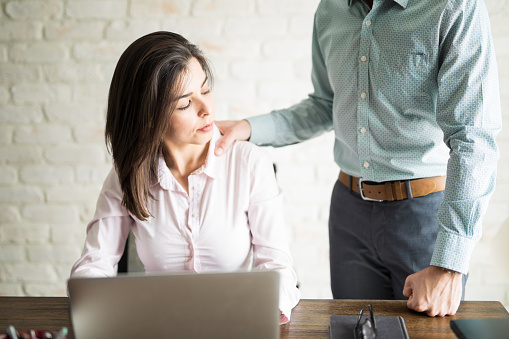 Abusive boss harassing a female colleague in the office while she looks uncomfortable and upset, sexual harassment, Sexual harassment Employee sacked for rape allegations